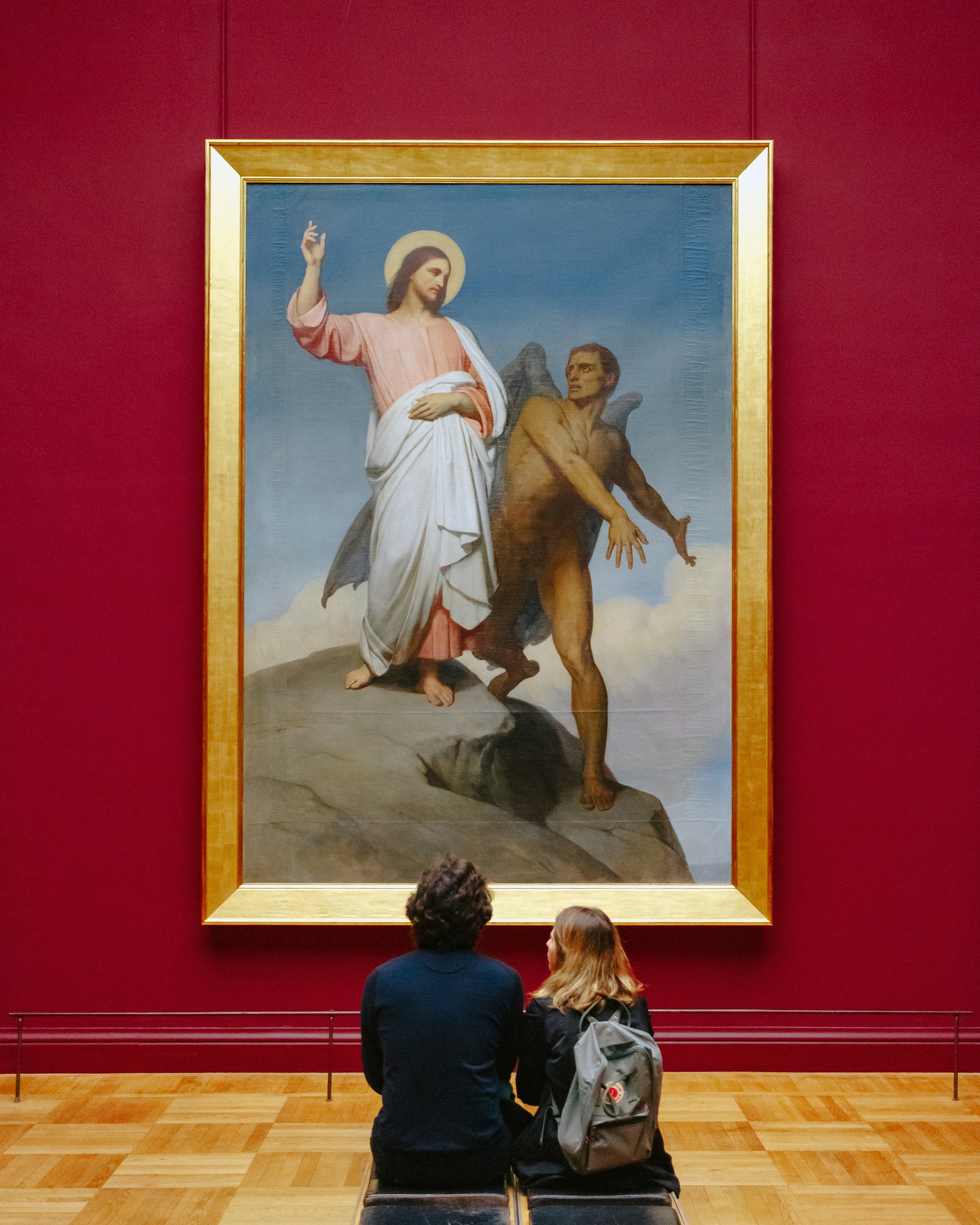 Dos visitantes contemplan pintura religiosa en museo de arte